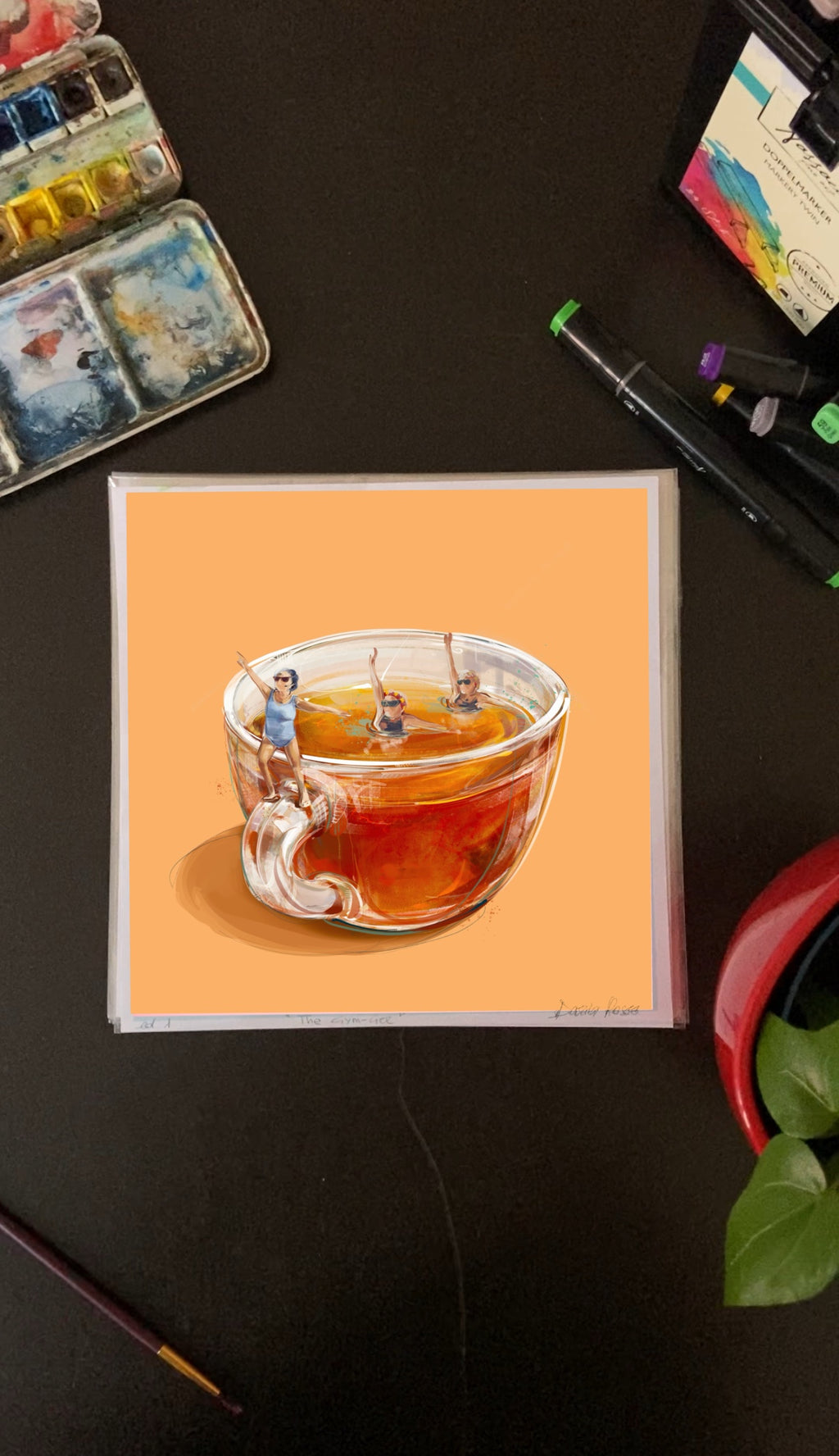 Artistic illustration of a teacup with tea bags on an orange background, placed on a dark surface with art supplies.